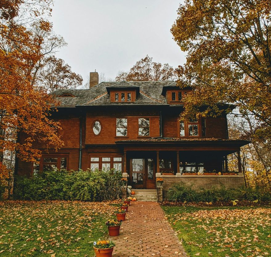 Brick-and-timber foursquare with a deep front porch under autumn trees